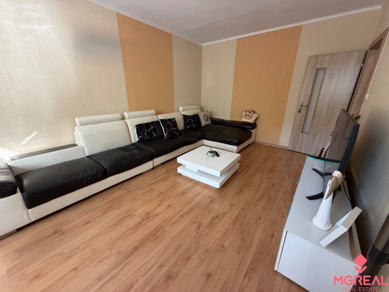 Living room with a sofa, television, and wooden decor flooring in a 3-room apartment.