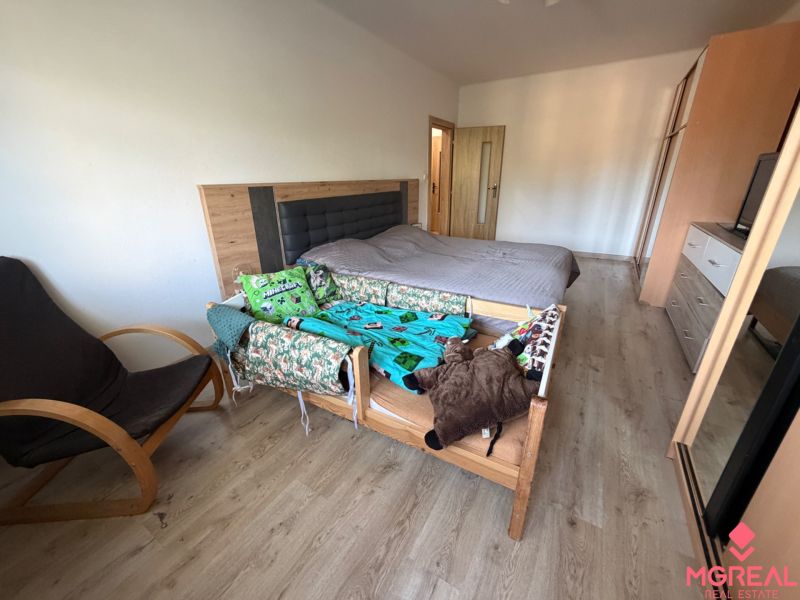 A bedroom in a 3-room apartment with a bed, an armchair, and a floor with a wooden decor.