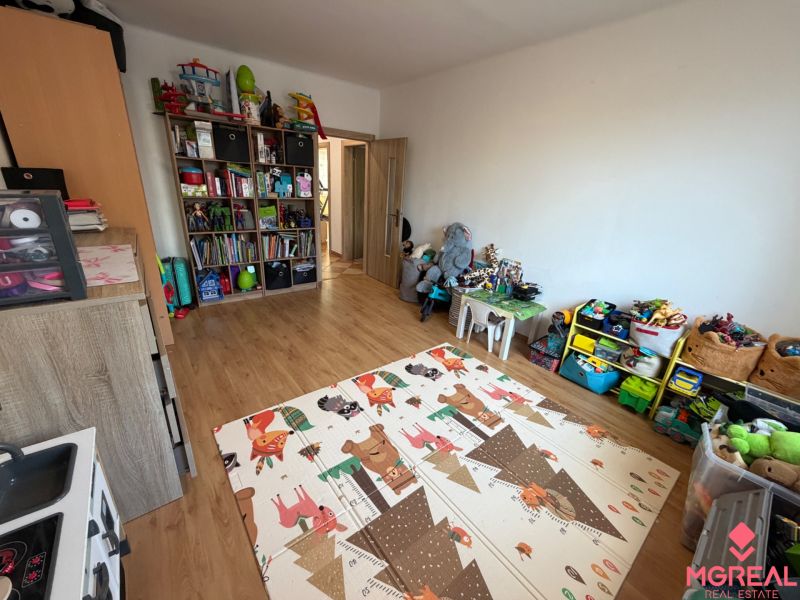 A children's room with a wooden decor floor full of toys and games in a 3-room apartment.