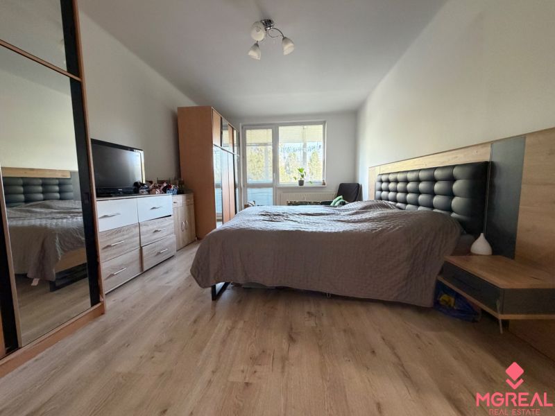 Bedroom in a 3-room apartment with a bed, wardrobe, and floor with wooden decor.