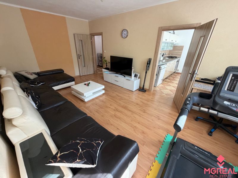 Living room in a three-room apartment with a wooden decor floor and a leather sofa.