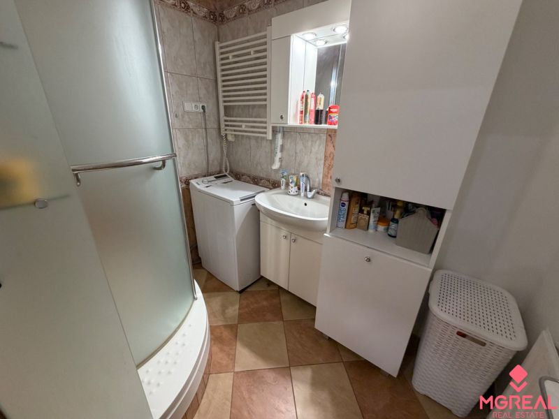 Bathroom in a 3-room apartment with a washing machine, shower cabin, and storage cabinets.
