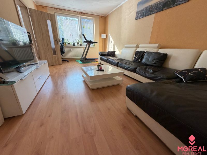 Living room with a leather sofa and a wooden decor floor in a 3-room apartment.
