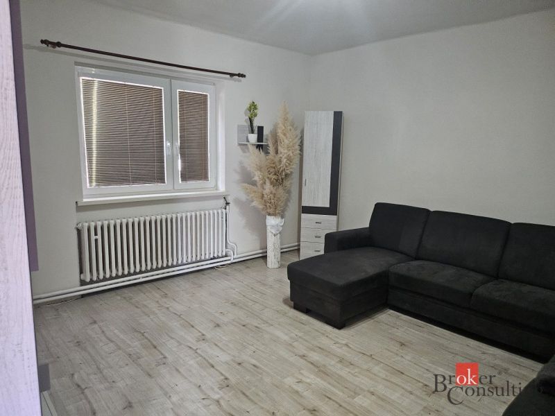 Living room with a television, wardrobe, window, and wooden decor flooring in a family house.