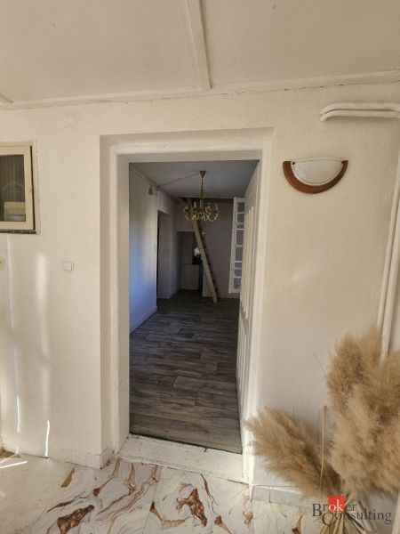 Living room with a television, wardrobe, window, and wooden decor flooring in a family house.