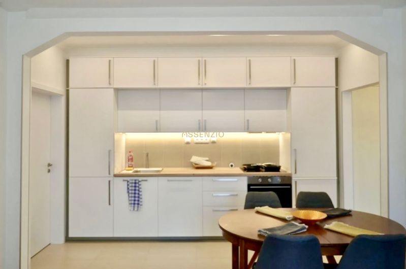 A kitchen in a 3-room apartment with a white kitchen unit and a dining table.