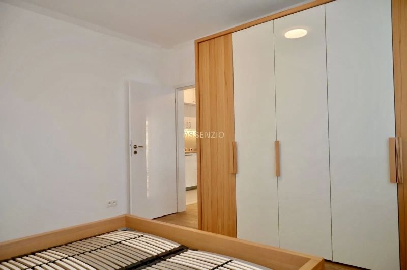 Wardrobe and bed frame in a 3-room apartment with a wooden decor floor.