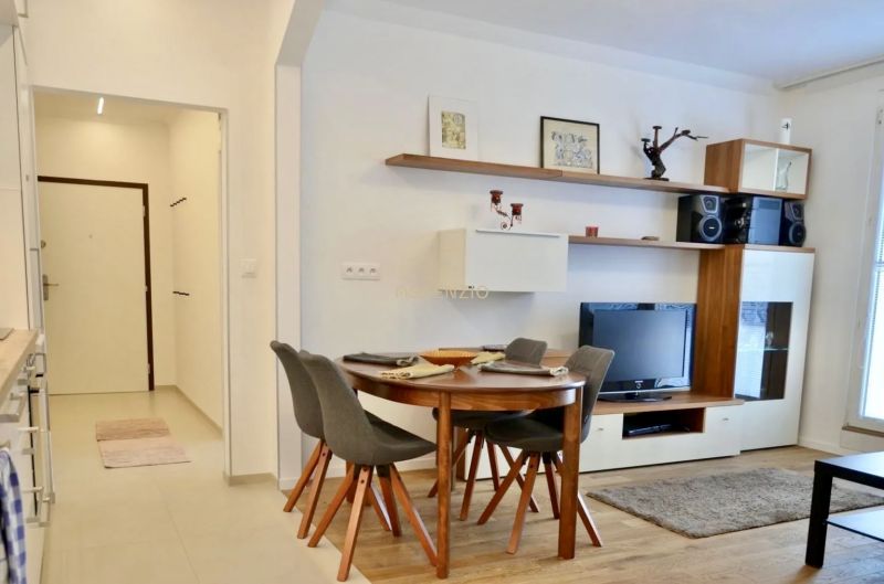 Dining area with four chairs and a TV in a 3-room apartment.