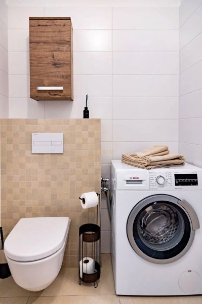 Bathroom in a 2-room apartment with a washing machine, toilet, and storage cabinet.