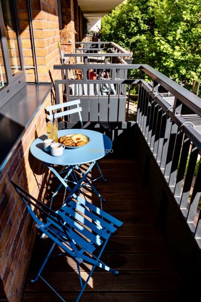 The balcony of a 2-room apartment with a blue table and chairs, wooden floor, reinforced railing.