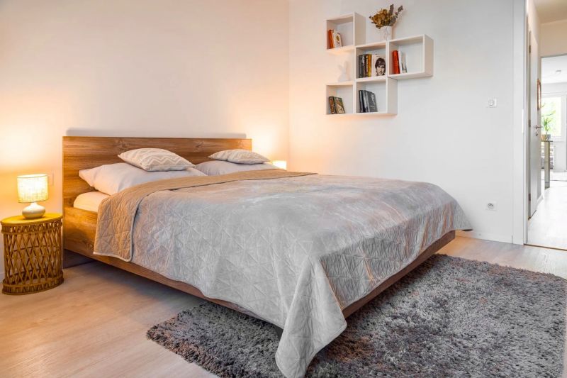 Bedroom in a 2-room apartment with a double bed, wood-patterned flooring, and a carpet.