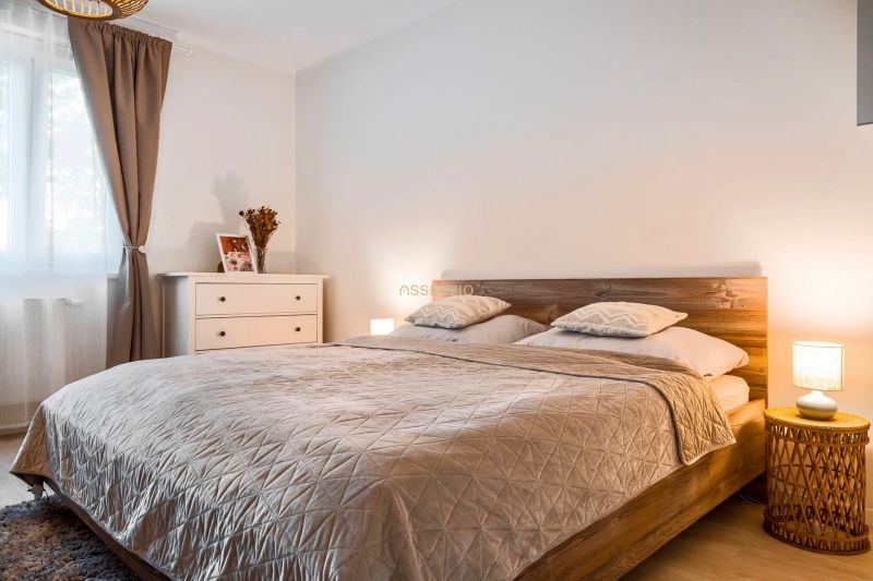 Bedroom in a two-room apartment with a bed, night lamps, and a floor with a wooden decor.