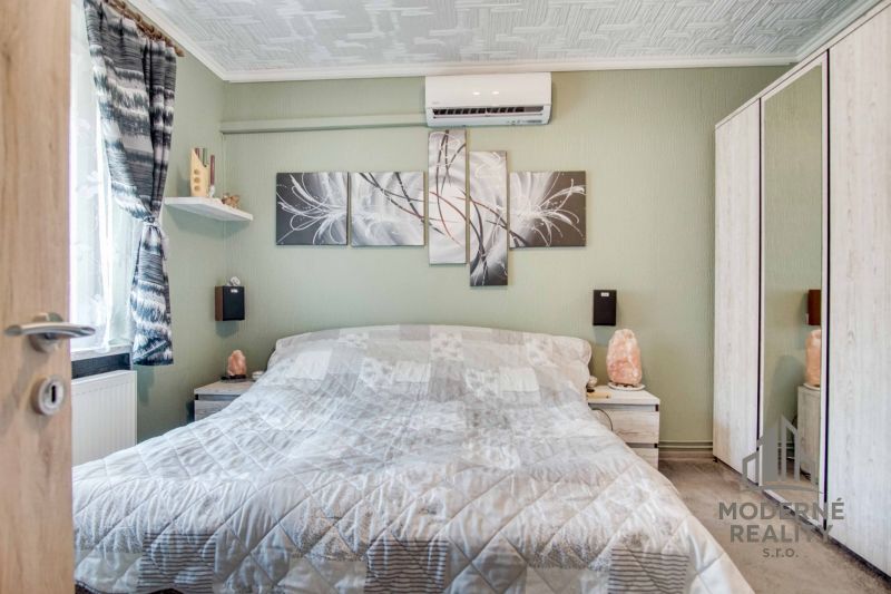 A bedroom in a 2-room apartment with air conditioning and abstract paintings on the wall.