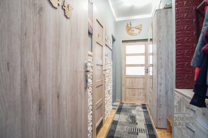 A narrow hallway of a 2-room apartment with wooden decor and furnishings.