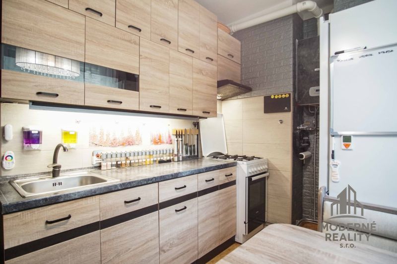 A kitchen in a 2-room apartment with a wooden decor floor and appliances.