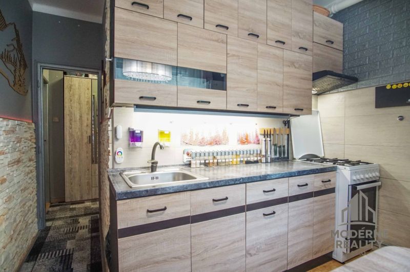 A kitchen in a 2-room apartment with a wooden decor floor and a practical kitchen unit.
