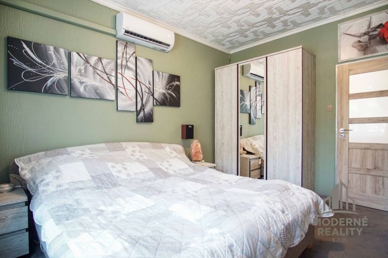 A bedroom in a 2-room apartment with air conditioning and art on a green wall.
