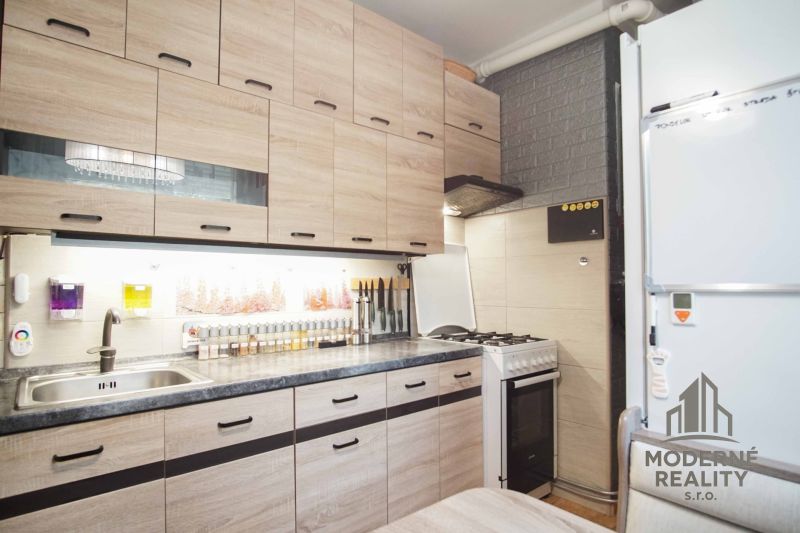 A kitchen in a 2-room apartment with wooden decorative cabinets and a gas stove.