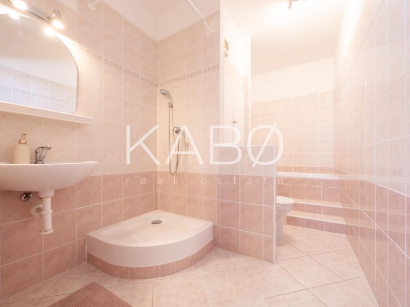 A bathroom with tiles and a shower in a 2-room apartment with soft shades of beige.