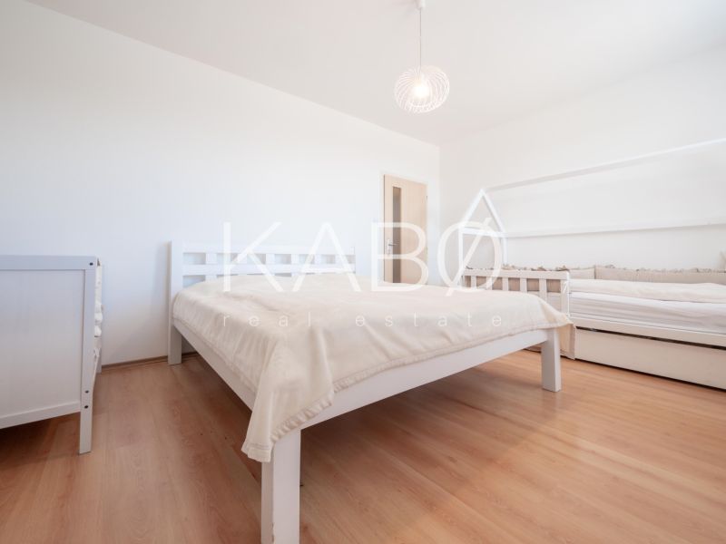 A bedroom with wood-patterned flooring, a double bed, and a child's bed.