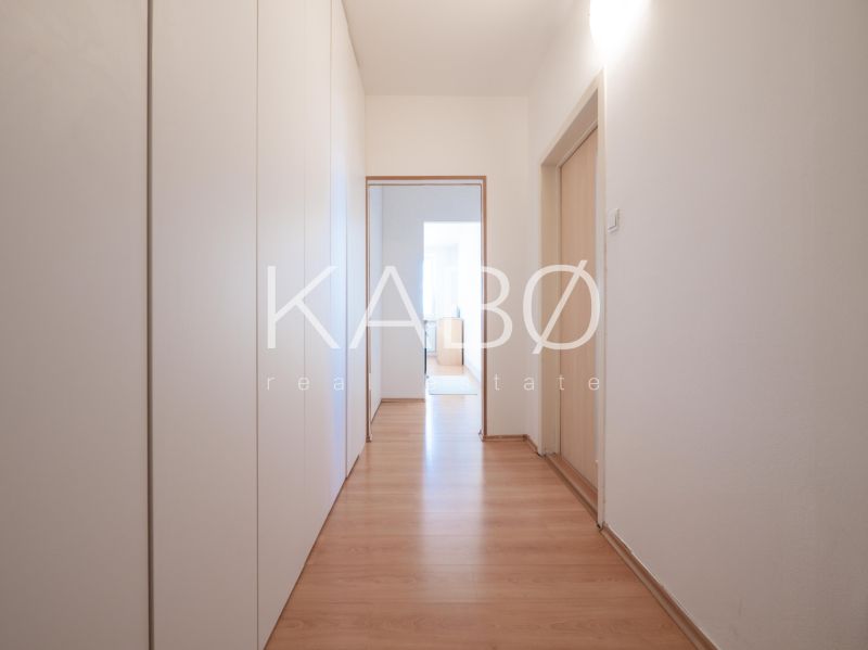 A hallway in a 2-room apartment with wardrobes and a wooden decor floor.