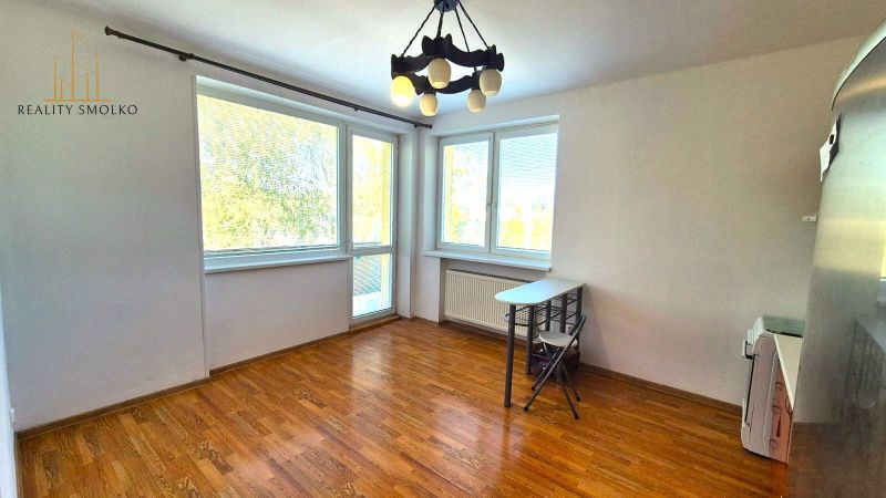 A room with large windows and a wooden decor floor in a studio apartment.