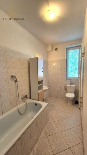 Bathroom with a bathtub and a window in a studio apartment, tiles and ceramics.