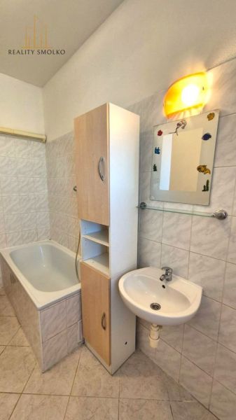 A bathroom with a bathtub and a sink in a studio apartment.