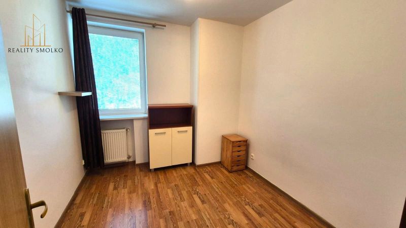 A room with a wooden decor floor in a studio apartment with light furniture.