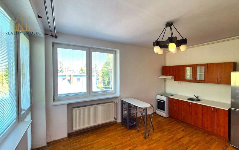 A kitchen in a one-room apartment with space for a dining area and a floor with a wooden decor.