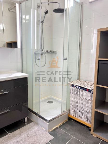Bathroom with a shower, cabinet, and laundry basket in a 2-room apartment.