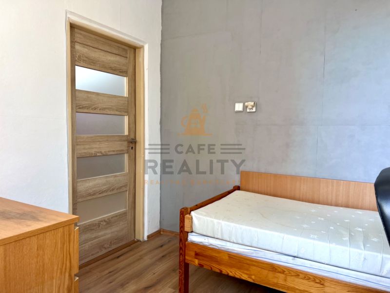 A room in a 2-room apartment with a bed and a floor with a wooden decor.