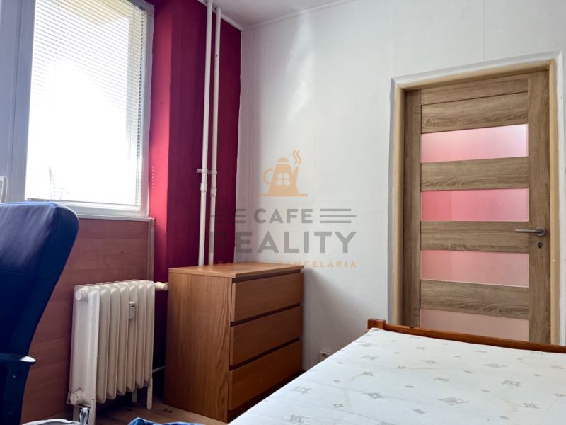 A room in a 2-room apartment with wooden decor, furniture, and a radiator.