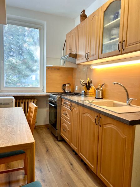 A kitchen in a 2-room apartment with wooden furniture and a floor with a wooden decor.