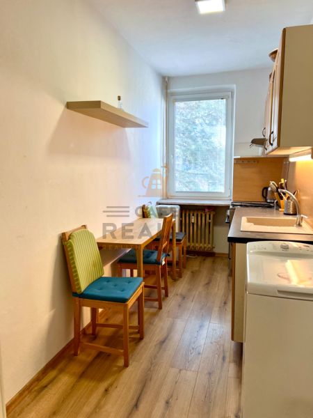 A kitchen with two chairs and a wooden-patterned floor in a two-room apartment.