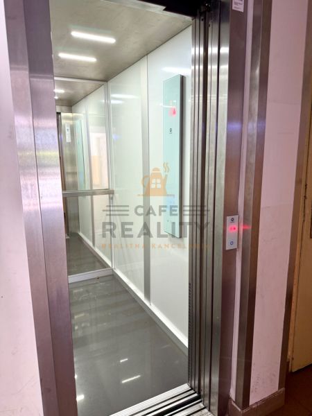 Elevator with a shiny floor in a 2-room apartment, white walls, illuminated ceiling.
