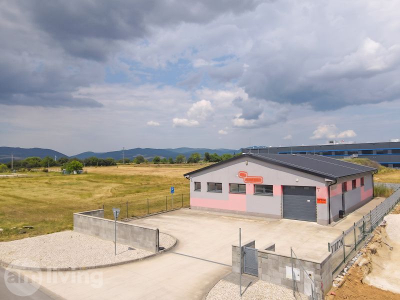 An industrial building in Nová Dubnica surrounded by fields and mountains.