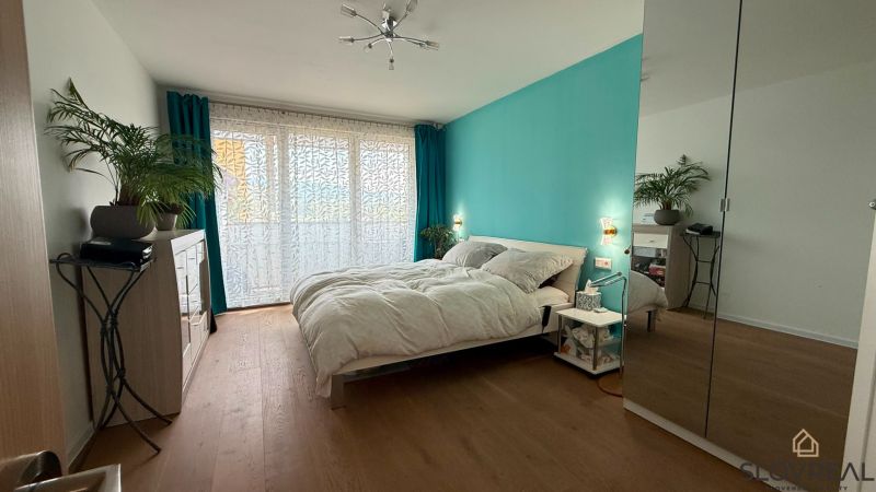 A bright bedroom with a turquoise wall, wood-patterned flooring, and a mirrored wardrobe in a four-room apartment.