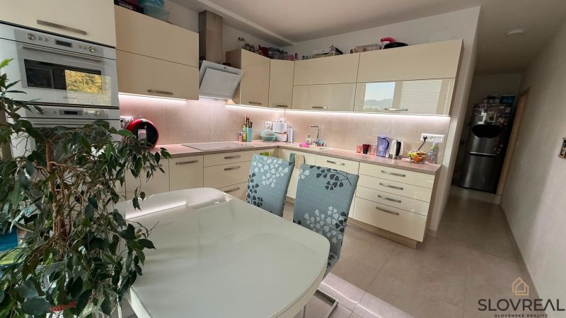 A kitchen in a 4-room apartment with white cabinets and a dining table.