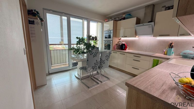 A kitchen in a 4-room apartment with a dining table and access to the balcony.