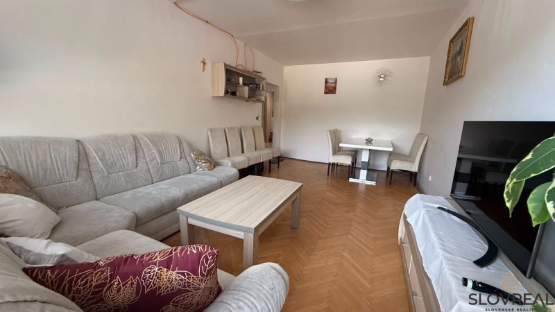 A living room in a 4-room apartment with a comfortable sofa set and a wooden decor floor.