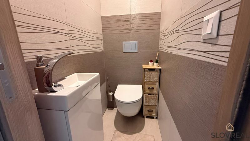 A cozy toilet with a simple sink and decorative tiles in a 4-room apartment.
