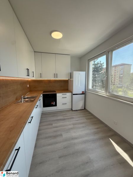 A kitchen in a 3-room apartment with white cabinets and a wood-patterned floor.