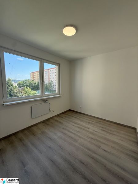 A room in a three-room apartment with a wooden decor floor and large windows.