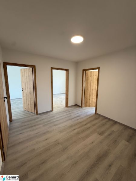 A room in a 3-room apartment with a wooden-decor floor and three doors.