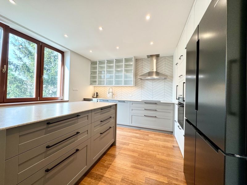A bright kitchen with a cooktop, sink, and wooden decor flooring in a 3-room apartment.