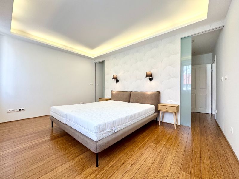 A bedroom in a 3-room apartment with a bed and a wooden decor floor.