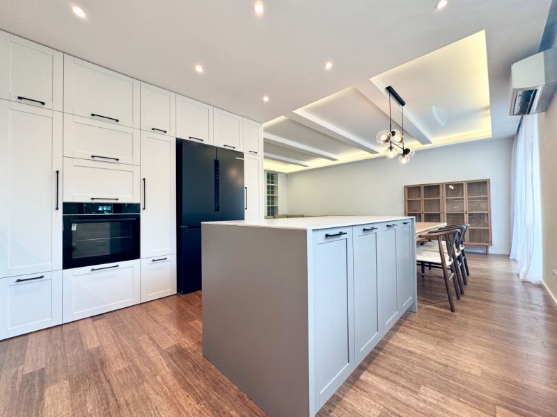 A kitchen with an island in a 3-room apartment, a floor with a wooden decor, dining room.
