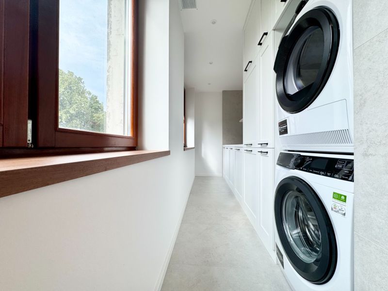 Practical laundry room in a 3-bedroom apartment with a washing machine and dryer on a white floor.