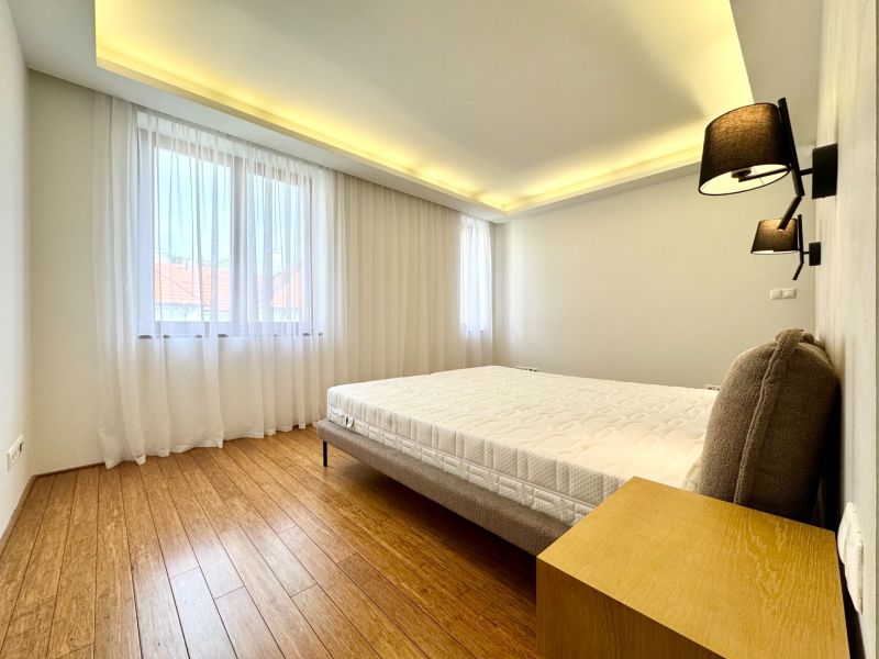 A bedroom in a three-room apartment with curtains and a wooden decor floor.
